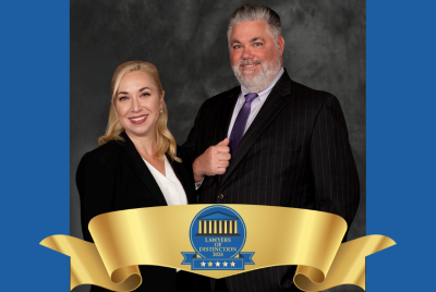 Attorney Cate Craig and Attorney Robert Scalise in suits with banner award for Lawyers of Distinction 2024