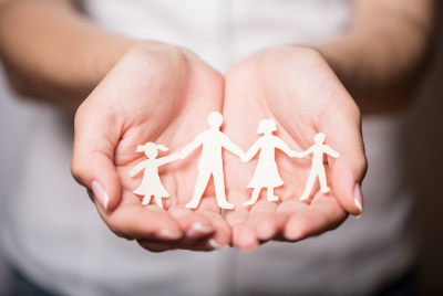 open hands holding paper cutout fo family of four